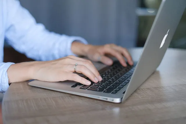 Hands using a laptop keyboard.