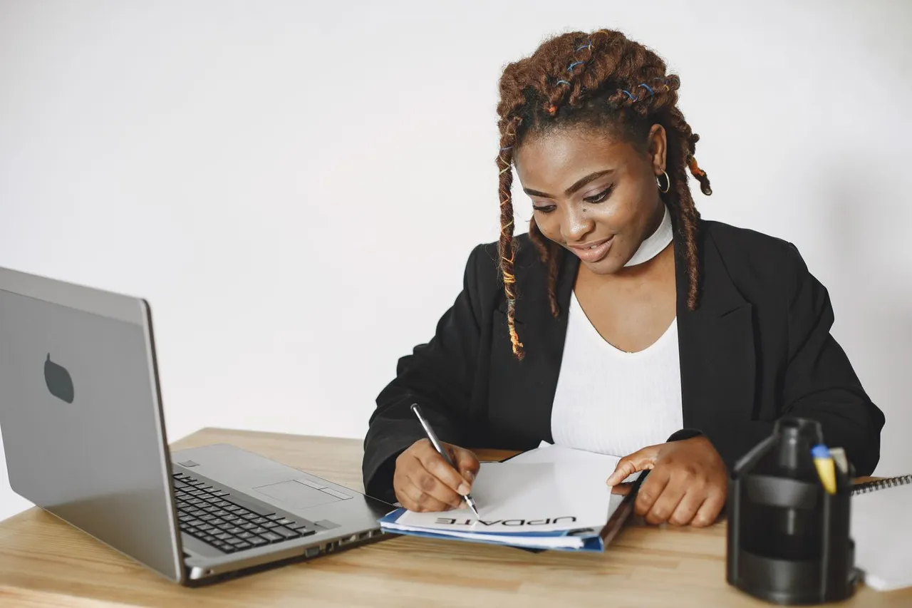 A woman reviewing documents beside her laptop.